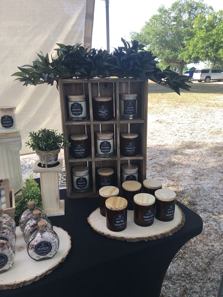 a table topped with jars and candles next to a potted plant on top of a wooden stand