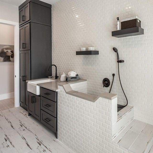 a bathroom with white tile and gray cabinets