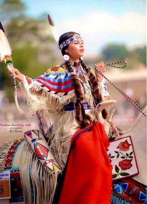 a native american man riding on the back of a white horse with feathers in his hair