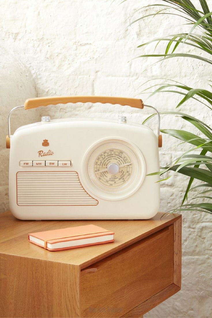 an old radio sitting on top of a wooden table next to a potted plant