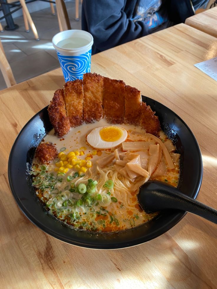 a bowl of ramen with an egg on top and noodles in the middle, sitting on a wooden table