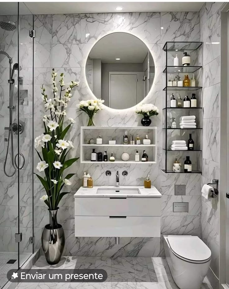 a bathroom with marble walls and flooring, white fixtures and flowers on the counter