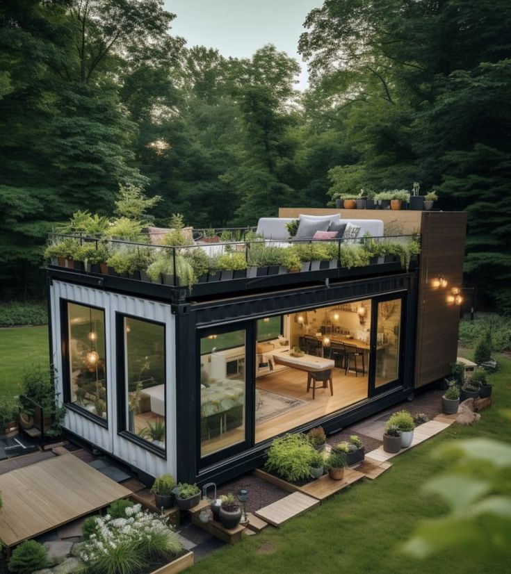 a house made out of shipping containers with plants growing on the roof and balcony area