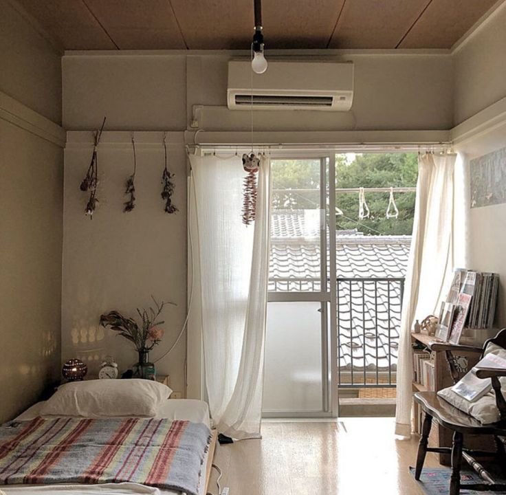 a bed sitting in a bedroom next to a window with curtains on top of it