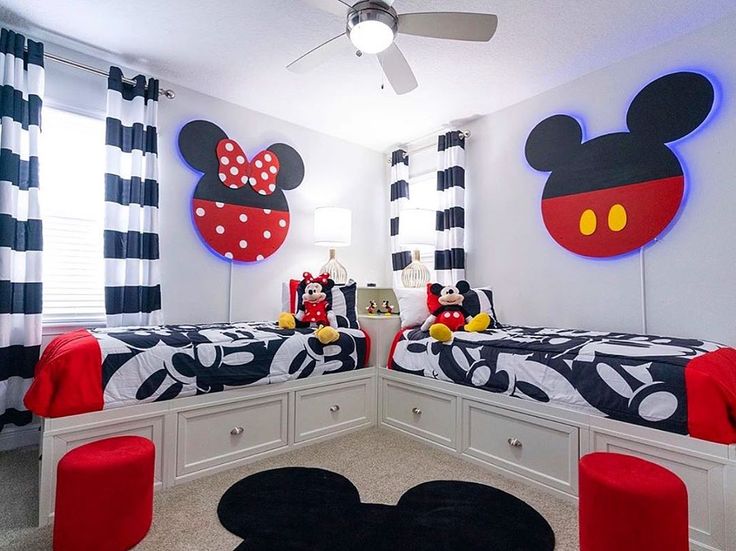 two beds in a room with mickey mouse decorations on the wall