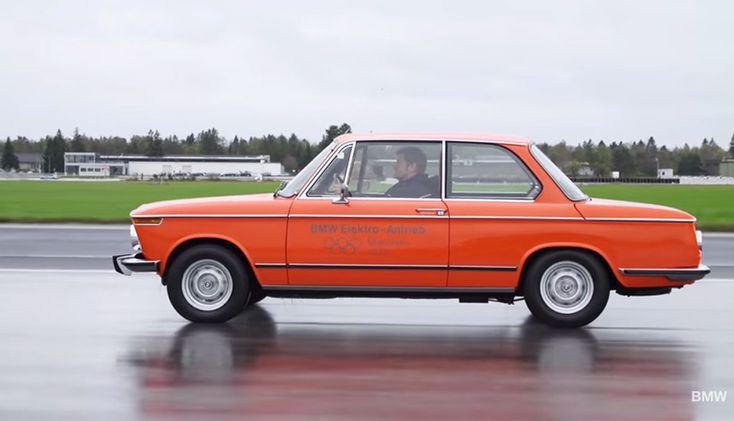 an orange car driving down a wet road