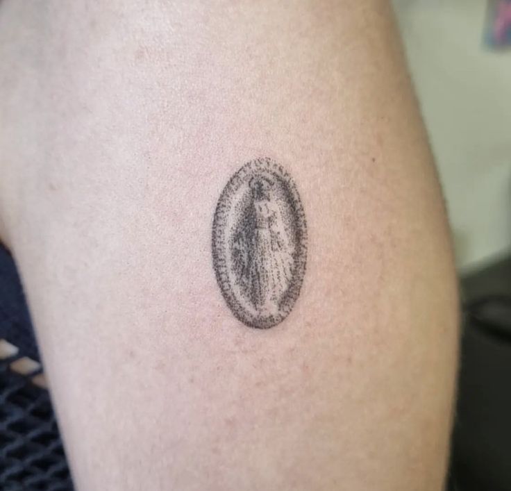 a woman's thigh with a small tattoo on her left leg and an oval frame around it