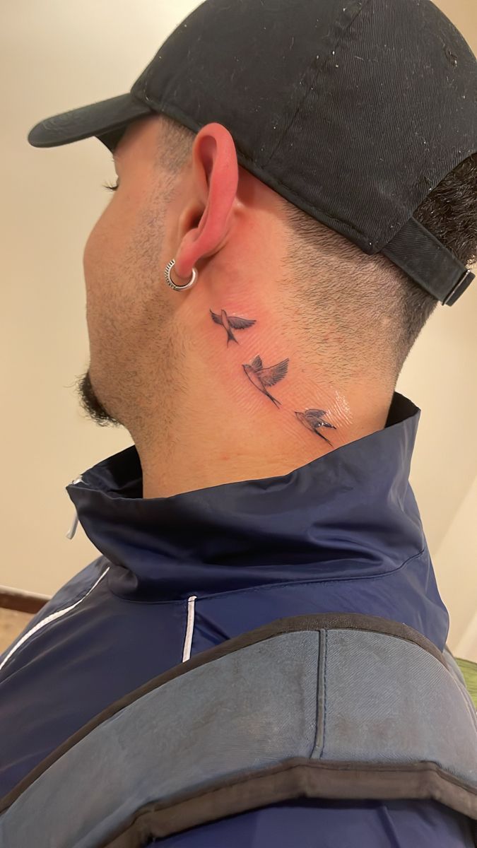 a man with a small tattoo on his neck and behind his ear is a bird