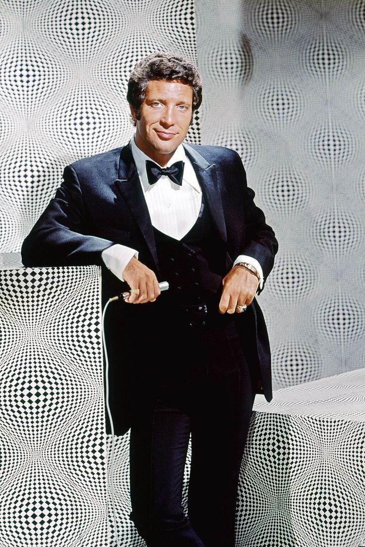 a man in a tuxedo standing next to a wall