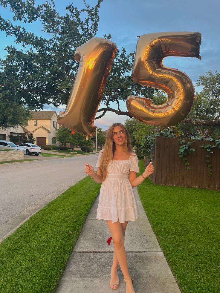 a woman is standing on the sidewalk with her hands in the air while holding two large balloons