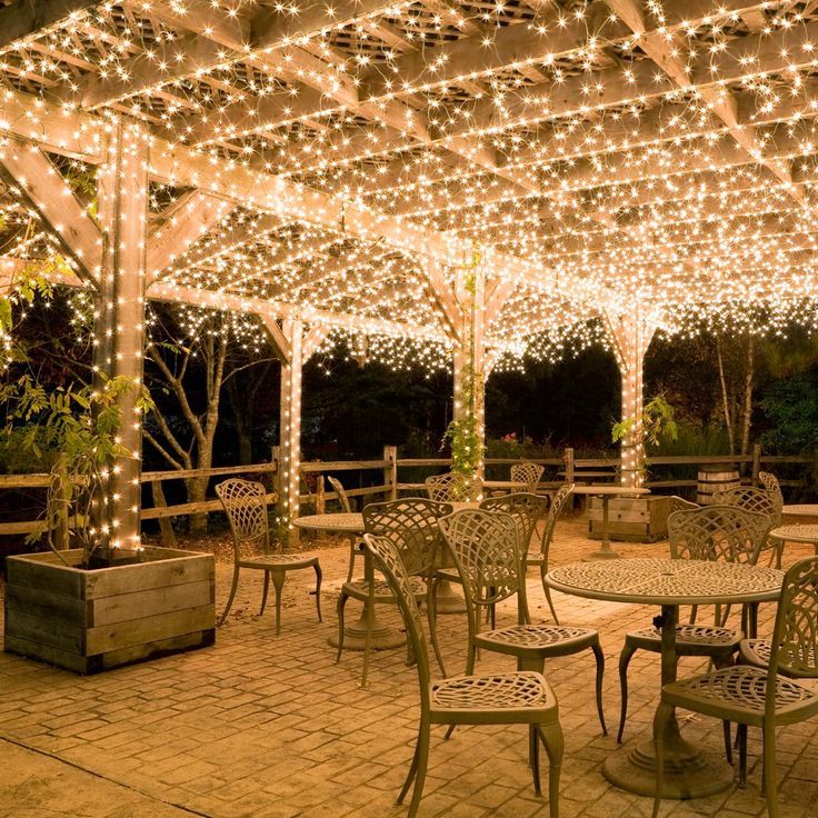 an outdoor dining area with tables and chairs covered in lights