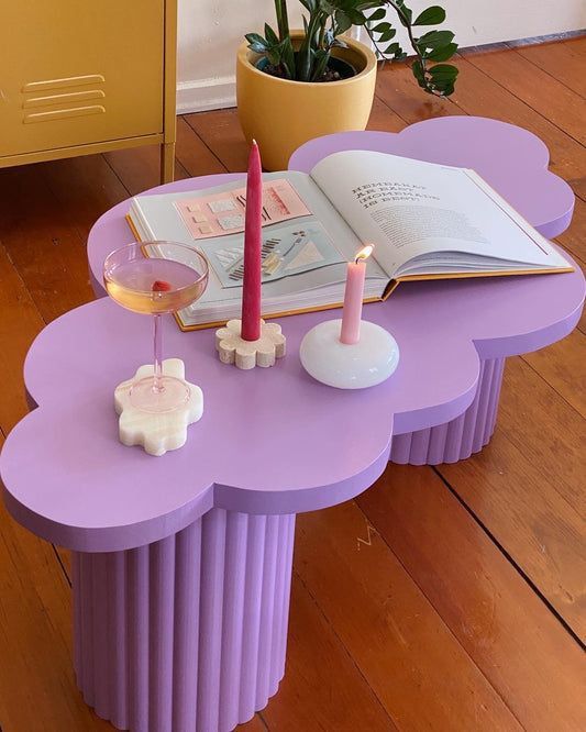 a purple table with two candles on it and an open book sitting on top of it