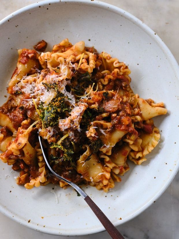 a white bowl filled with pasta and broccoli on top of a marble table