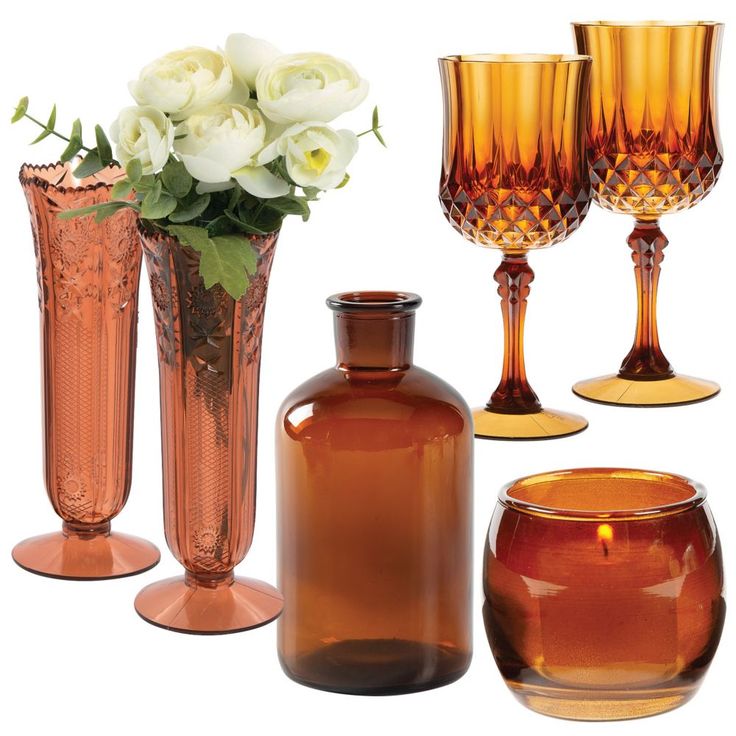 several vases and glasses are arranged on a white background, including one with flowers in it