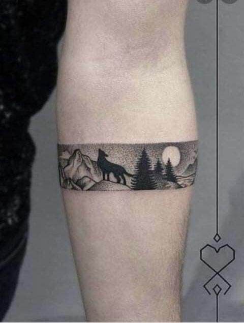 a man's leg with a tattoo on it that has mountains and trees in the background