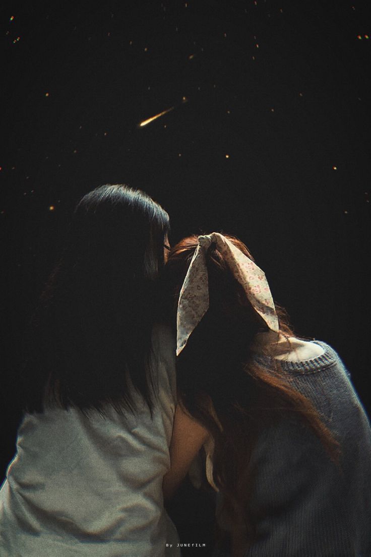 two women are kissing in the dark with stars above them and one woman is wearing a white shirt