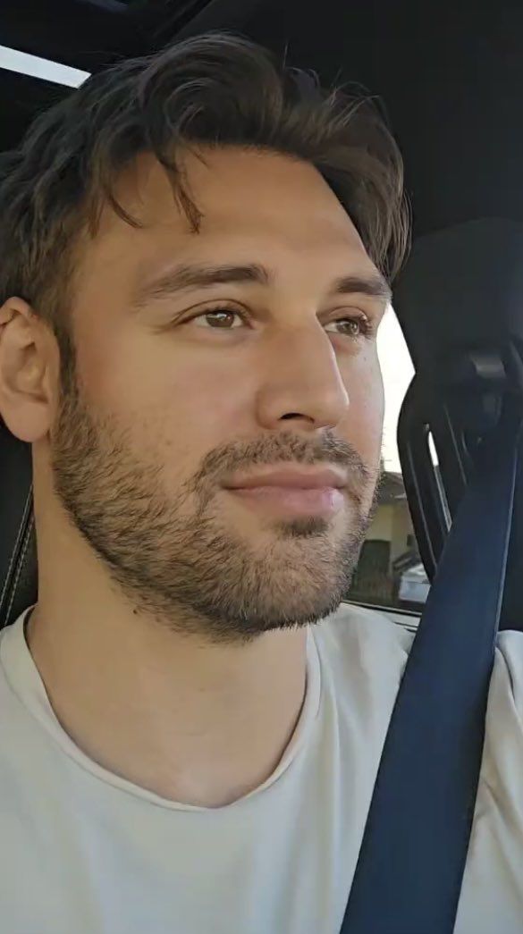 a man sitting in the back seat of a car wearing a white t - shirt