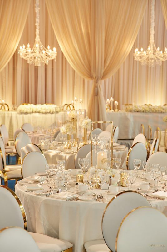 the tables are set with white linens and gold trim