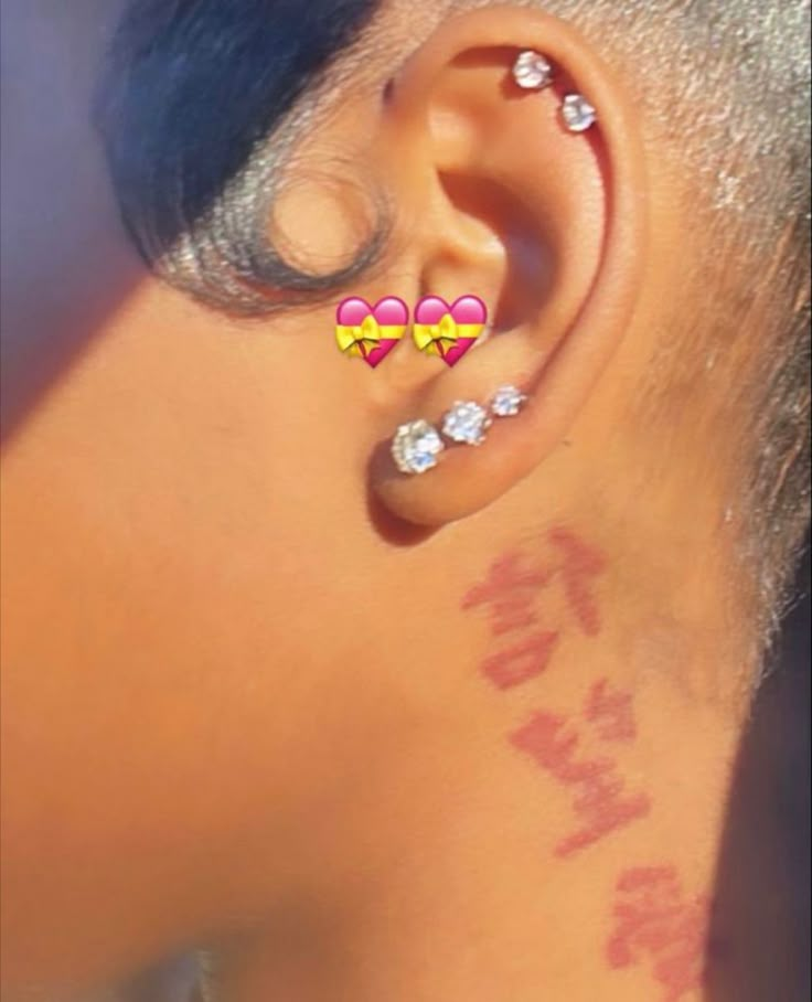 the back of a woman's ear with three hearts on it