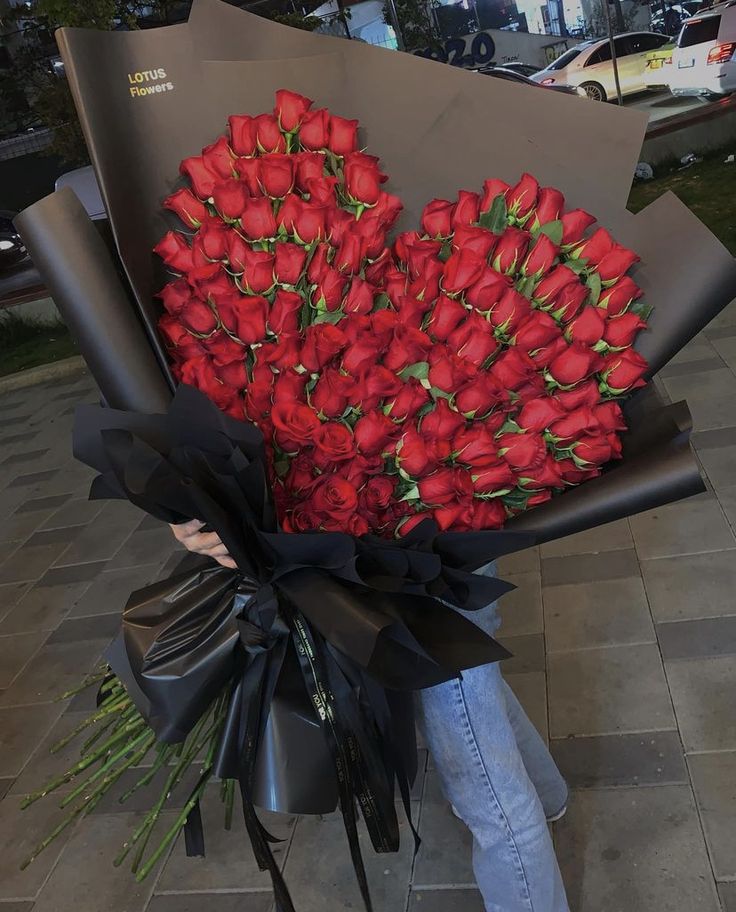 a person holding a large bouquet of red roses