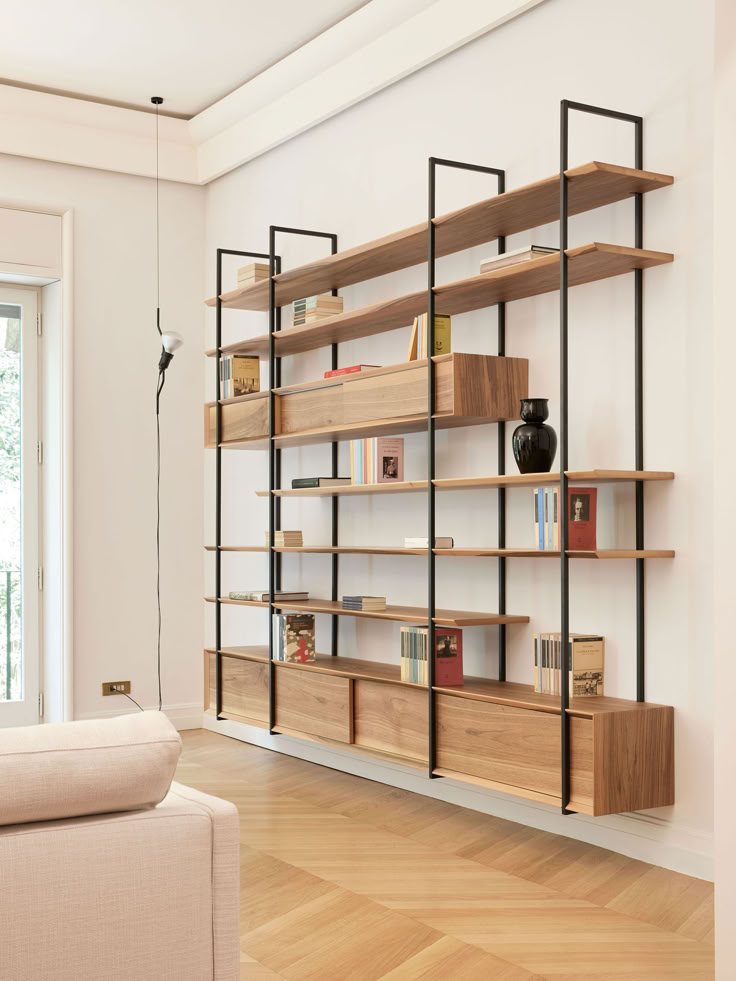 a living room filled with furniture and a book shelf next to a white couch on top of a hard wood floor