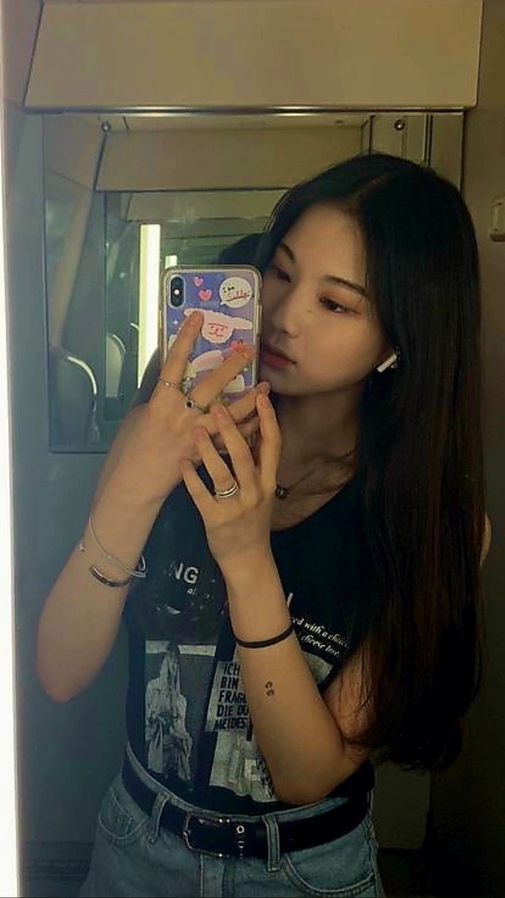 a young woman taking a selfie in front of a mirror with her cell phone