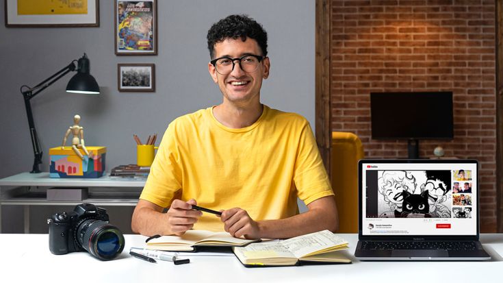 a man sitting at a desk with a laptop computer and notebook in front of him