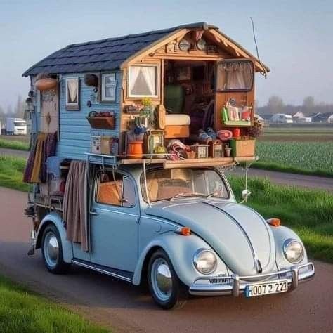 an old vw bug is parked on the side of the road in front of a tiny house