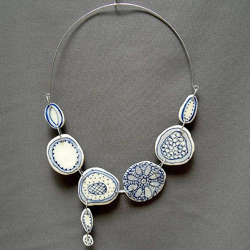 a necklace with blue and white designs hanging from it's side on a gray background