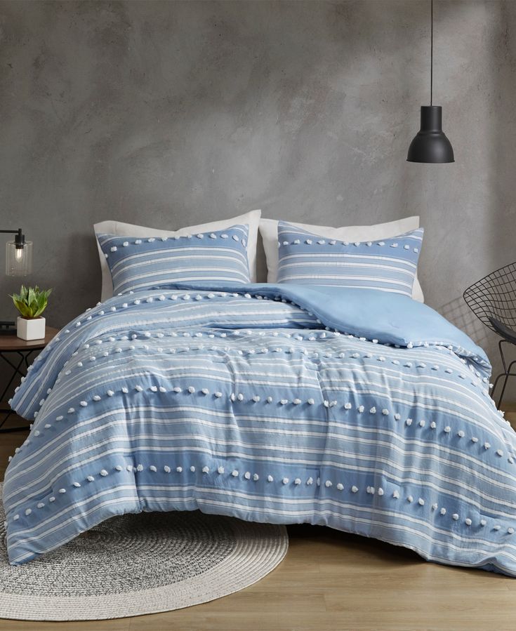 a bed with blue and white striped comforter in a gray room next to a table