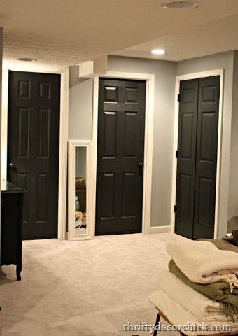 an empty room with black doors and white carpet