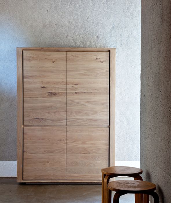 two stools sit next to a wooden cabinet in a room with white walls and concrete flooring