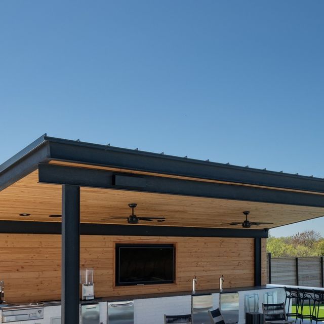 an outdoor kitchen and dining area on a sunny day with blue sky in the background