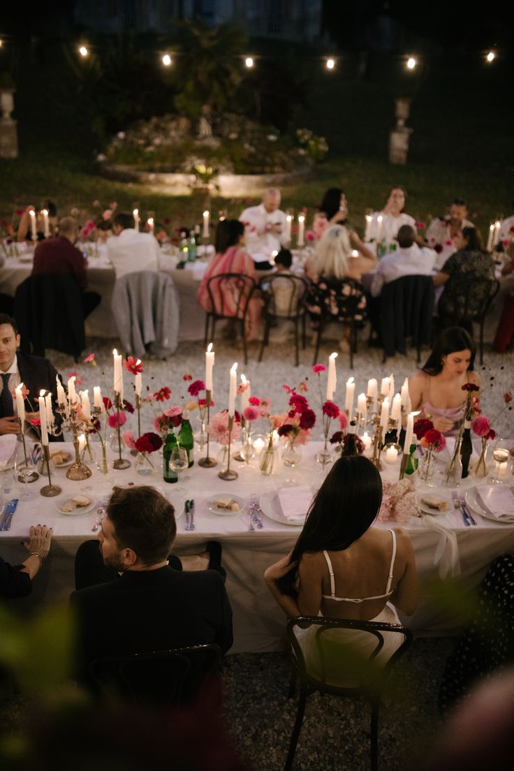 a group of people sitting around a table with candles in the shape of flowers on it