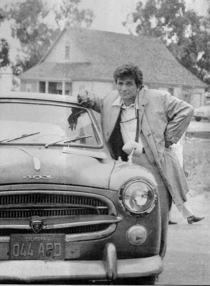 a man leaning on the hood of an old car