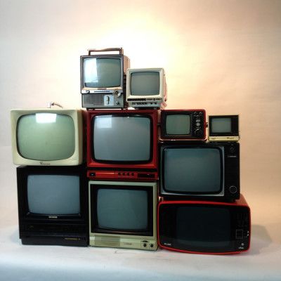 a pile of old televisions sitting on top of each other in front of a white background