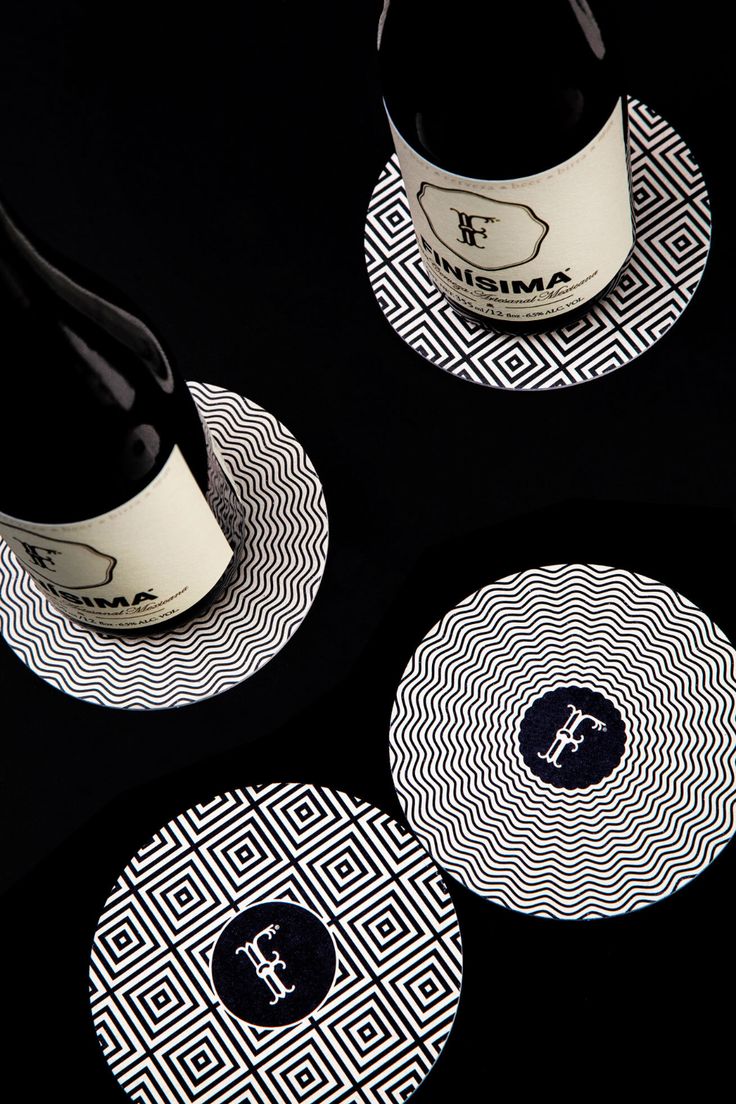 two wine bottles are sitting next to each other on coasters that have black and white designs