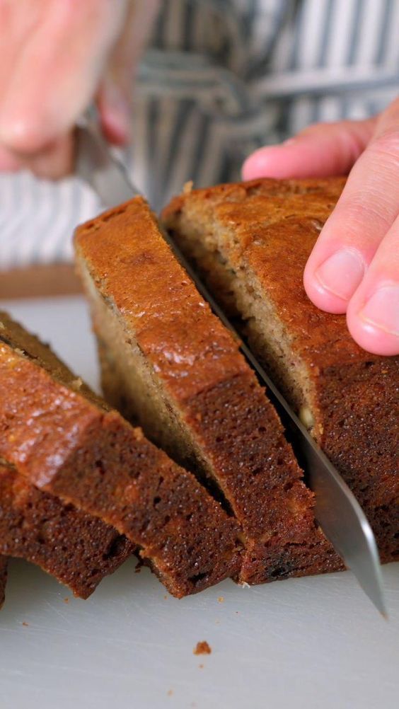 someone cutting into a loaf of bread on top of a white plate with a knife