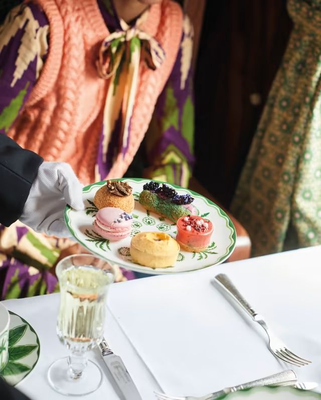 a person holding a plate with pastries on it at a table in front of other people