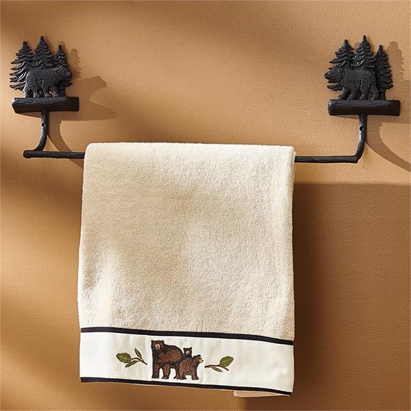 a towel hanging on the wall next to two black iron hooks with bear and pine trees