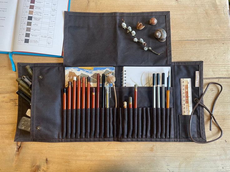 Handmade from chestnut waxed cotton, brass press fasteners and a brown leather tie.  ▪️24 individually formed pockets (for pencils and pens up to 8mm in diameter)  ▪️ roomy pencil case with side gussets and press studs to keep everything secure ▪️2 large pockets, which will hold  7"x5" sketchbooks ▪️A small pocket suitable for a ruler ▪️A large top flap - when folded out this makes a nice area to place some of your equipment. Folded down and your roll rolled up, it keeps everything securely where it should be.  ▪️A leather tie keeps your roll neatly and securely fastened when folded up.    Equally useful in the home, studio or out on wild adventures! Initially I made an artists roll for myself and couple of years later it's still going strong and has developed a great patina. I've tweaked Leather Pencil Case, Leather Tie, Press Studs, Waxed Cotton, Pencil Case, Chestnut, Ruler, Brown Leather, Sketch Book