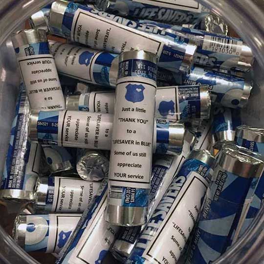 a glass bowl filled with lots of blue and white rolled up newspaper tubes on top of each other