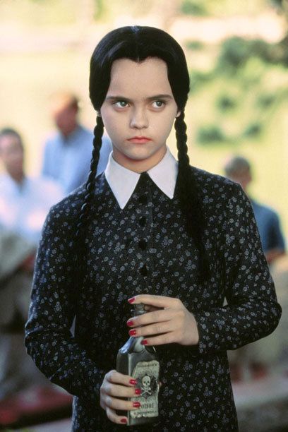 a woman with braids holding a beer in her hand and looking at the camera