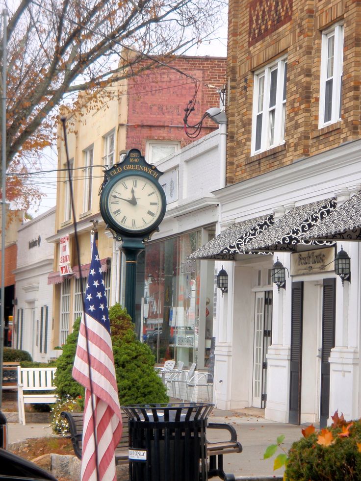 an american flag is on the sidewalk next to a clock