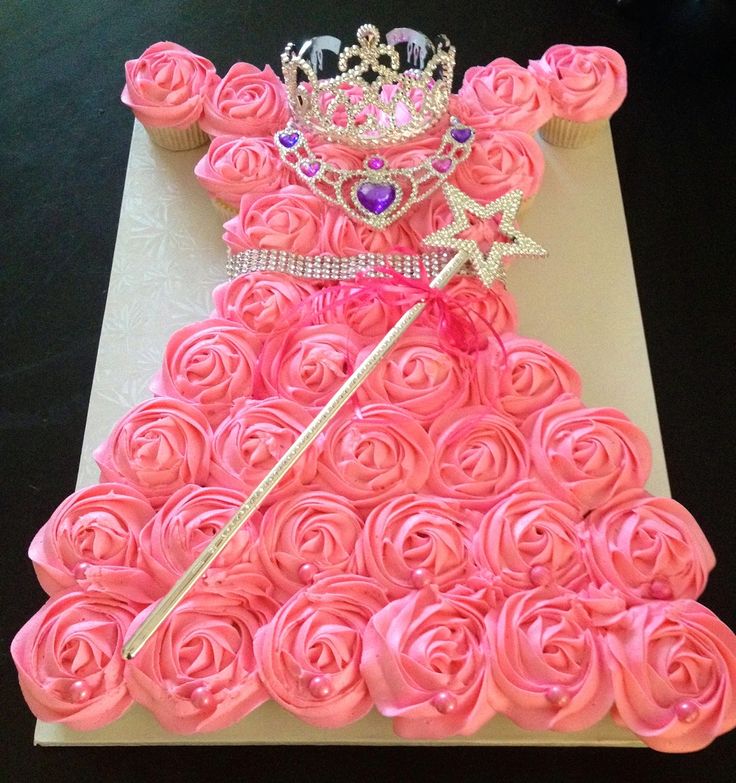 a cake made to look like a princess dress with pink roses and a tiara