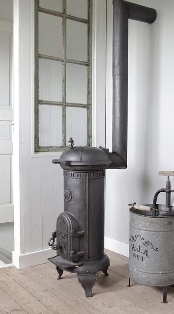 an old fashioned stove is in the corner of a room next to a metal bucket