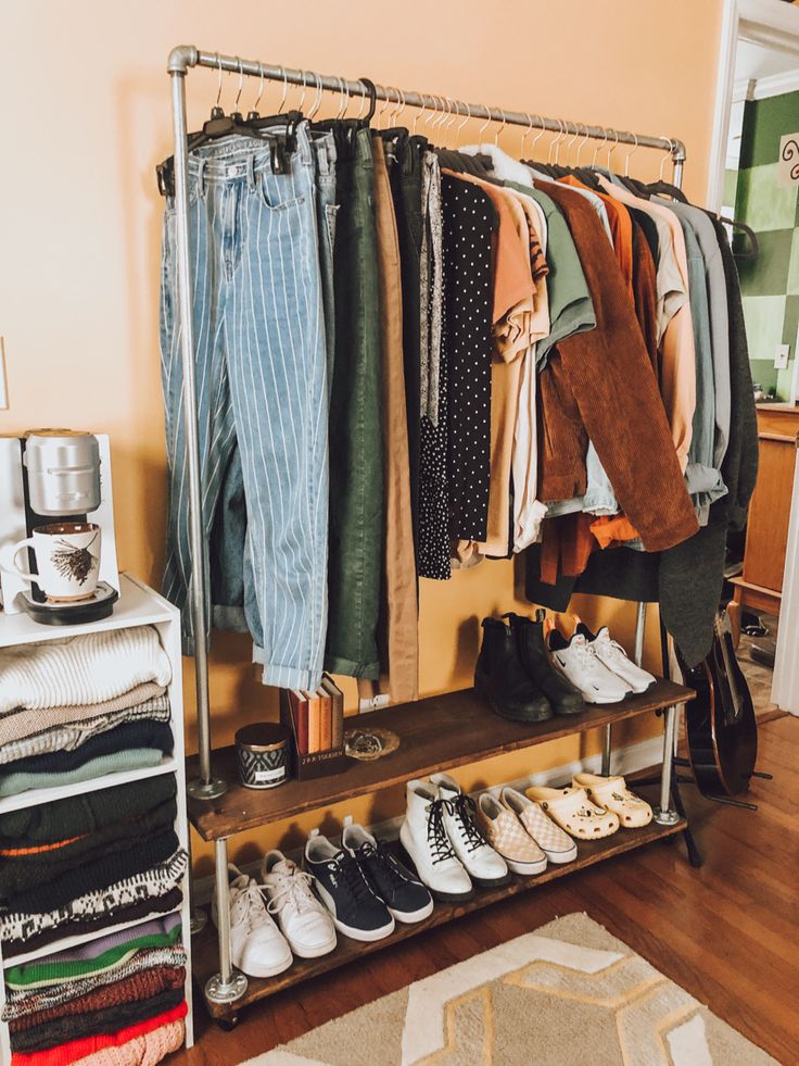 an organized closet with shoes, pants and sweaters hanging on the rack in front of it