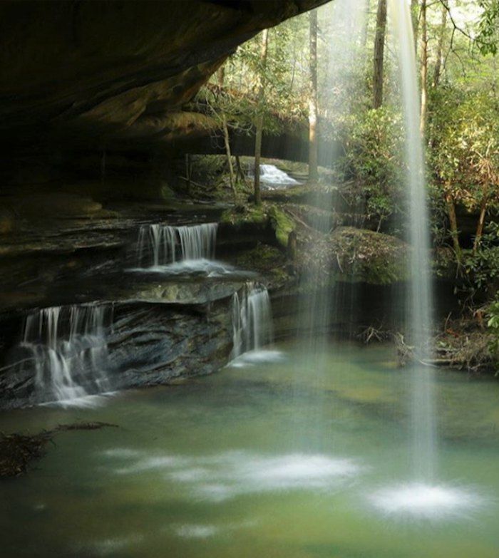 there is a waterfall in the middle of the forest with green water flowing from it