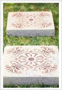 two cement blocks sitting in the grass with designs painted on them and one is laying down