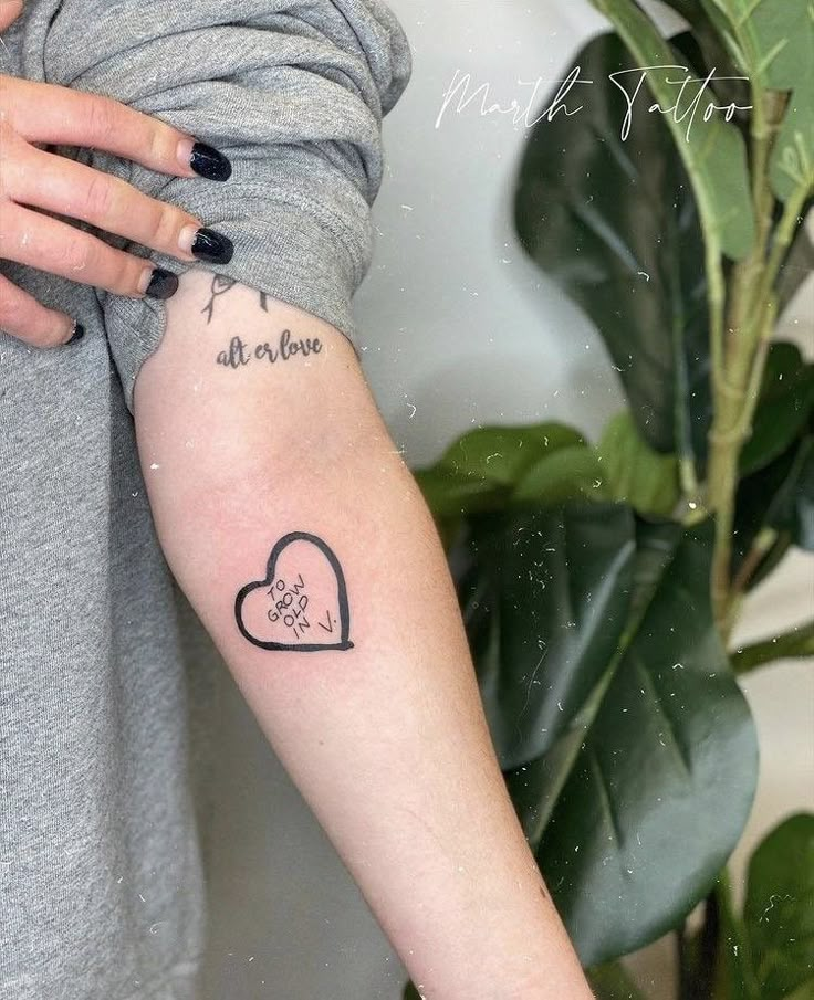 a woman with a heart tattoo on her arm